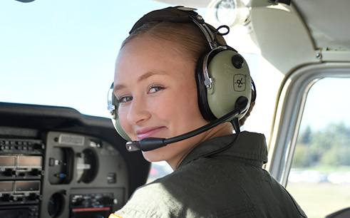 A Civil Air Patrol cadet in a headset at the controls of a light aircraft